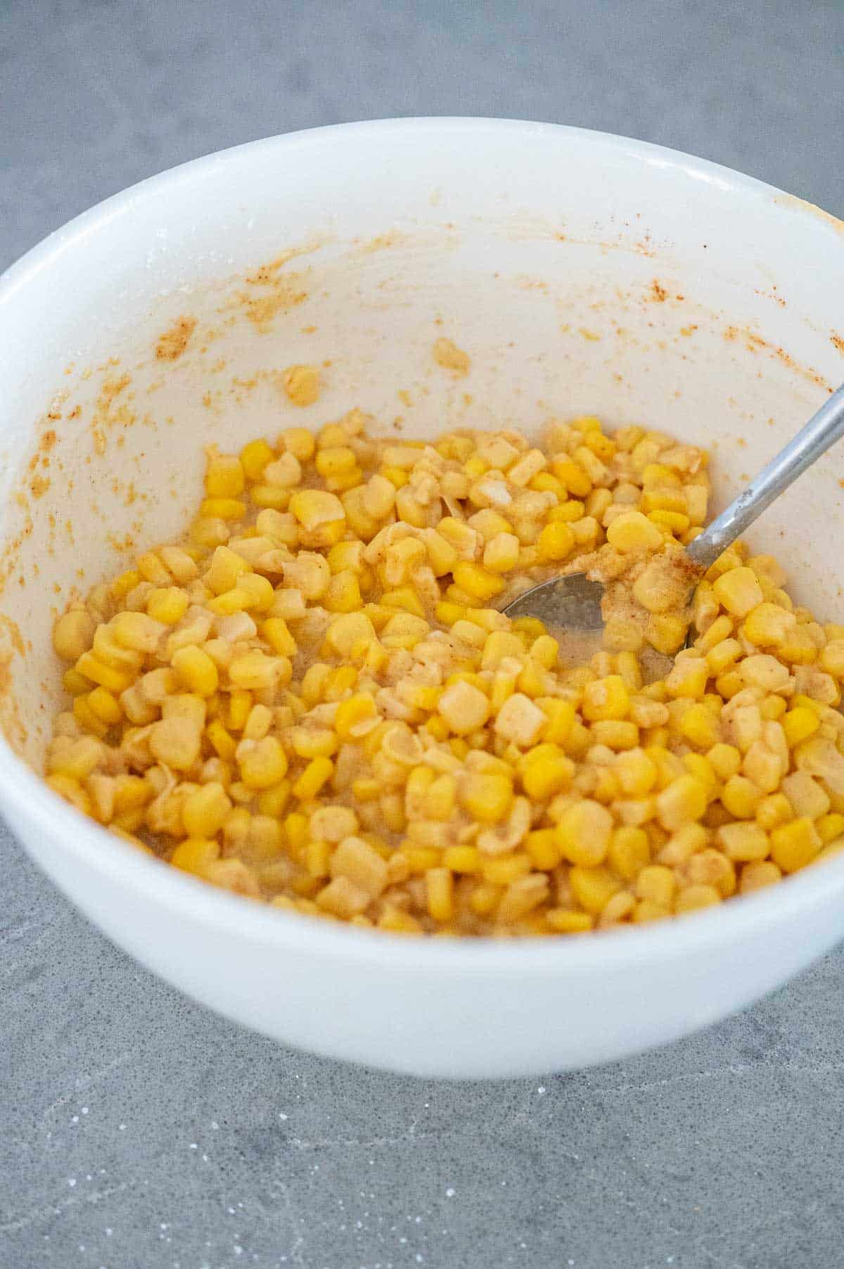 a bowl of corn fritter batter with a spoon in