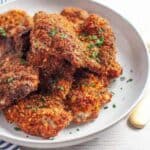 breaded paprika chicken thighs on a white plate