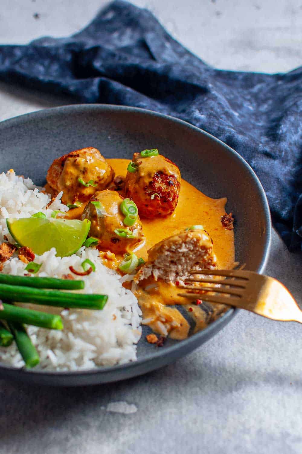 Thai Chicken Meatballs With Peanut Sauce and rice being eaten with a fork