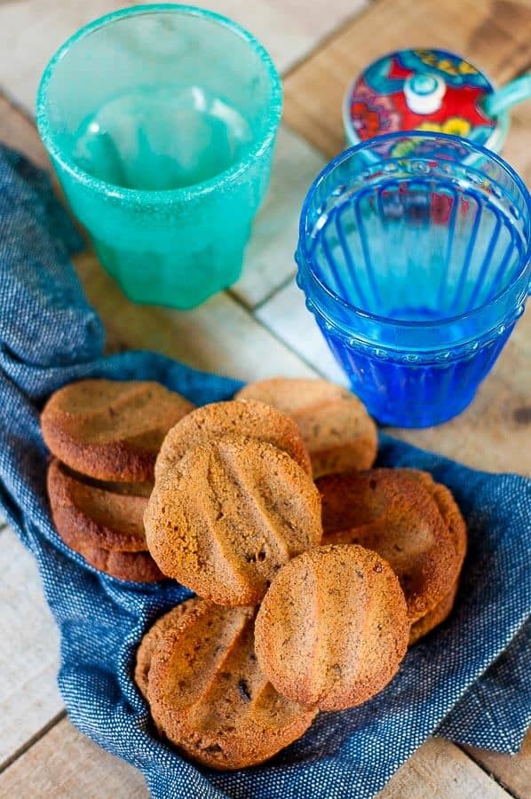 Ginger biscuits on a blue tea towl on a wooden table with two glasses