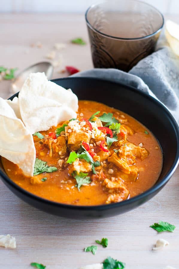 Pressure cooker chicken curry in a black bowl with pappadaum