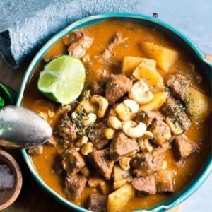 book of beef massaman curry in a bowl with peanuts and lime wedge