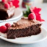 A single slice of mud cake on a plate with 3 raspberries
