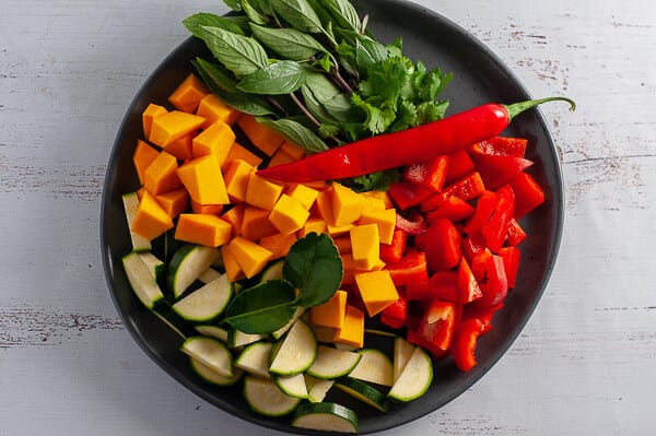 chopped pumpkin, zucchini, capsicum, chilli and basil on a plate