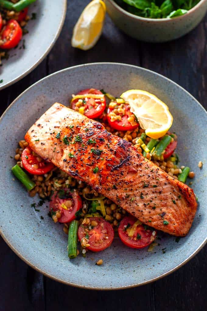 Salmon with leeks, tomatoes, lentils and beans in a bowl