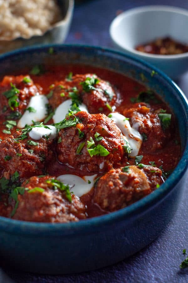 A bowl of slow cooker moroccan meatballs with sour cream and corriander