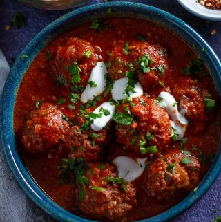 A bowl of slow cooked moroccan meatballs drizzled with sour cream and corriander