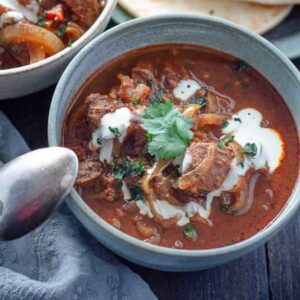 a grey bowl with rogan josh beef curry and a drizzle of coconut cream