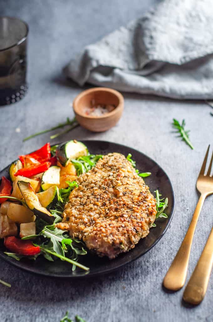 Quinoa crusted chicken on a plate with knife and fork