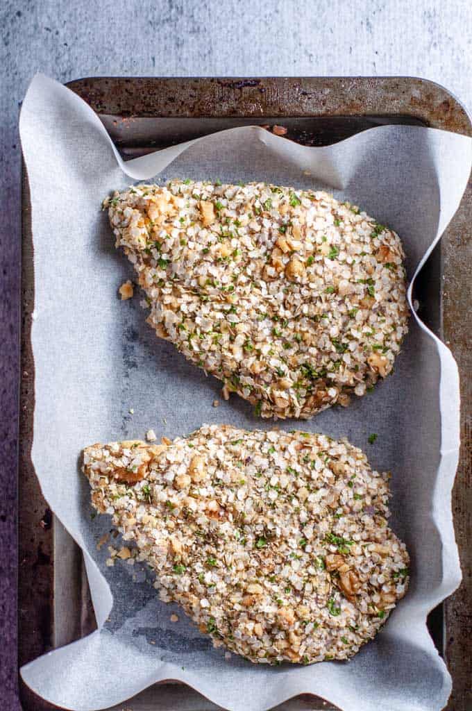 Two pieces of quinoa crusted chicken in baking tray