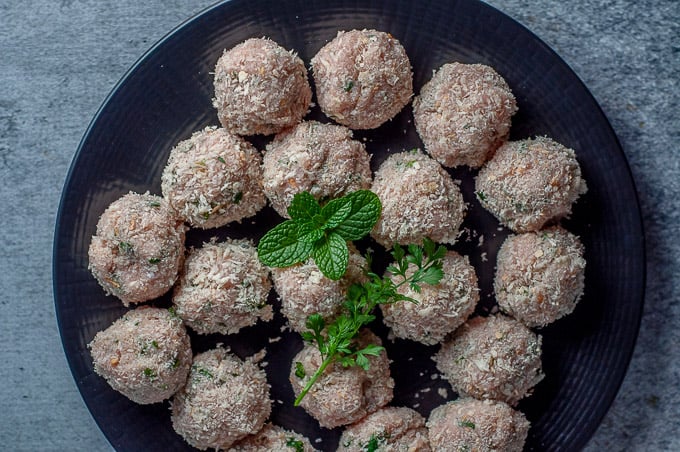 Uncooked thai chicken meatballs on a black plate