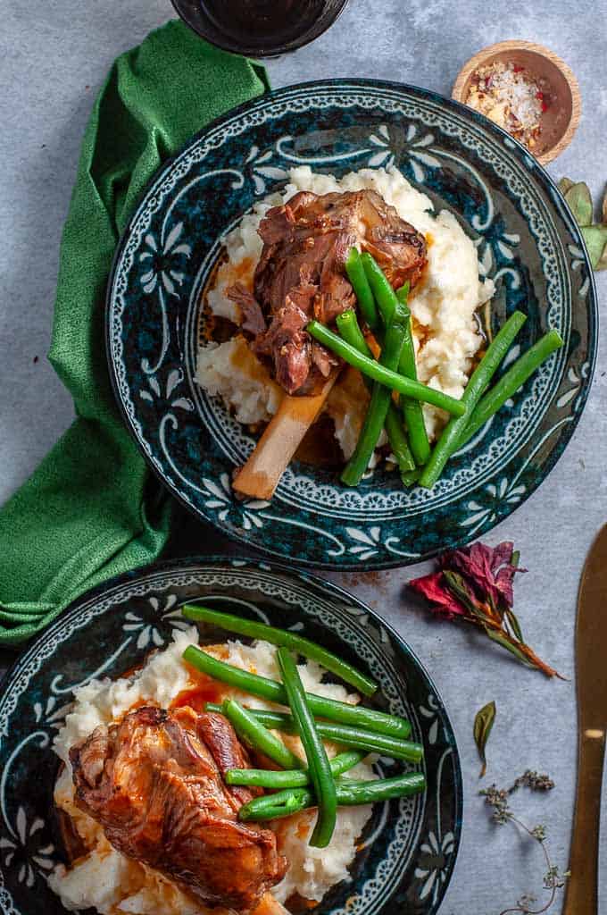 Two plates of pressure cooker lamb shanks and mash