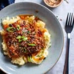 asian lemon chicken thighs on mashed potato in a blue bowl