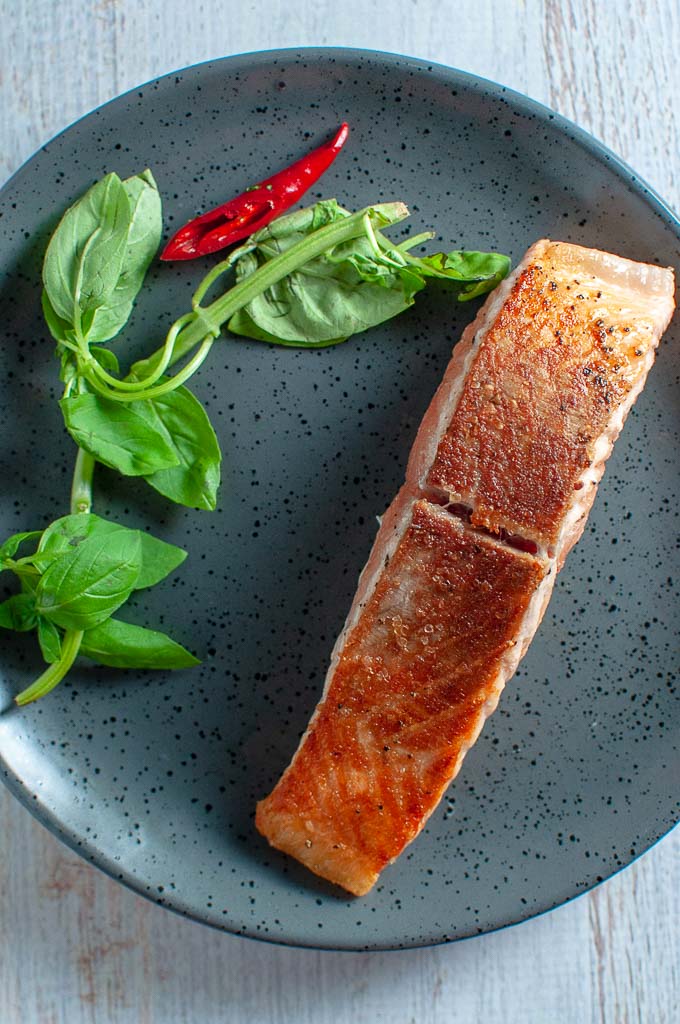 a piece of pan fried salmon on a grey plate