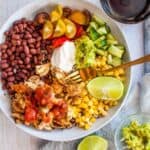 chicken burrito in a bowl with fork and lime wedge