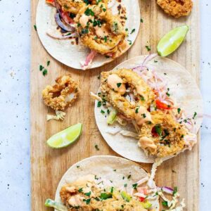 wooden board with 3 crunchy calamari tacos