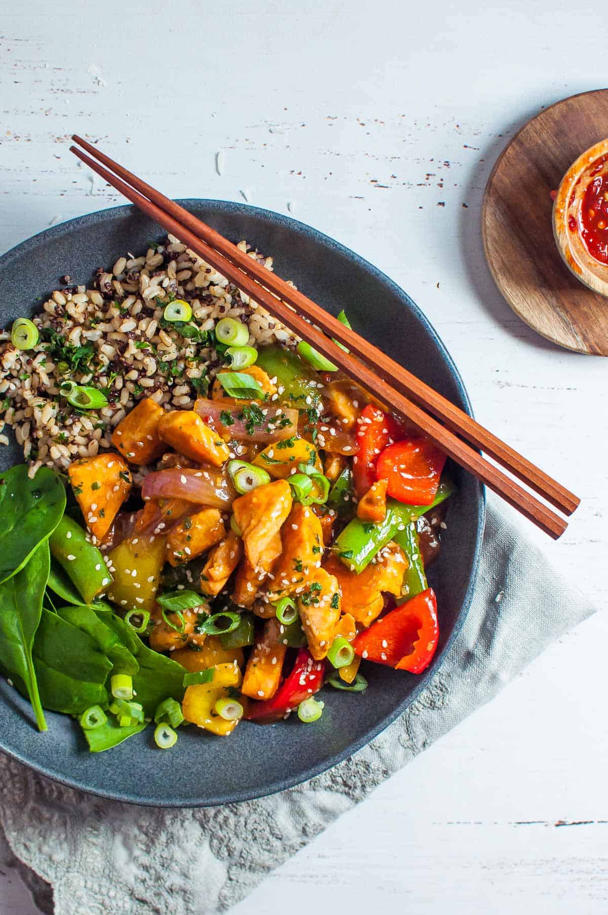 stirfry salmon with rice and spinach in a dark grey bowl