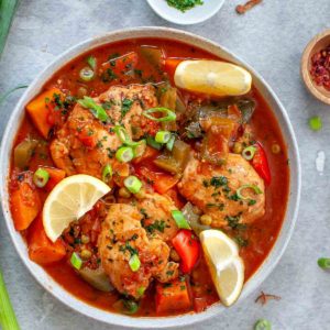 Chicken afritada stew in a bowl with lemon