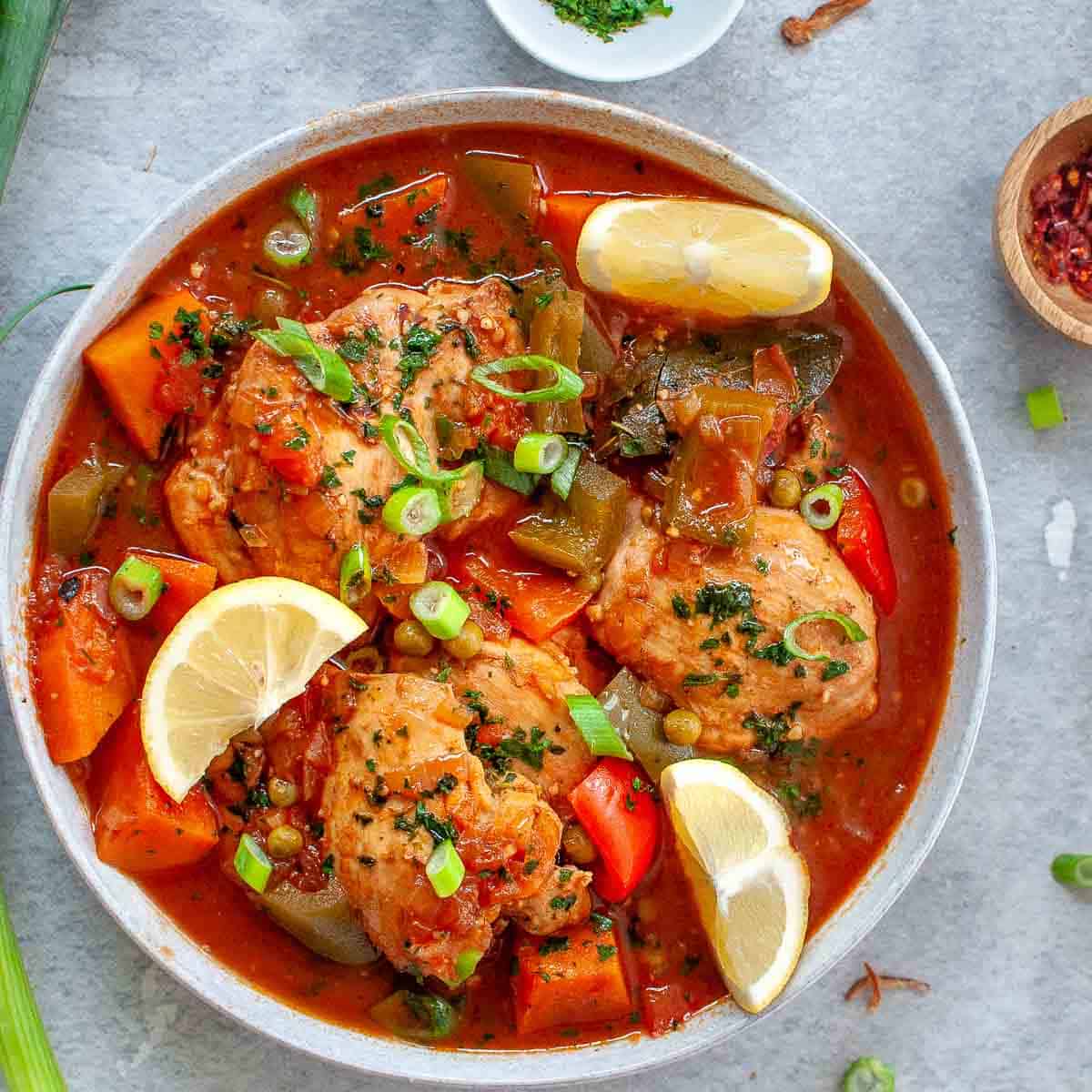 Chicken afritada stew in a bowl with lemon