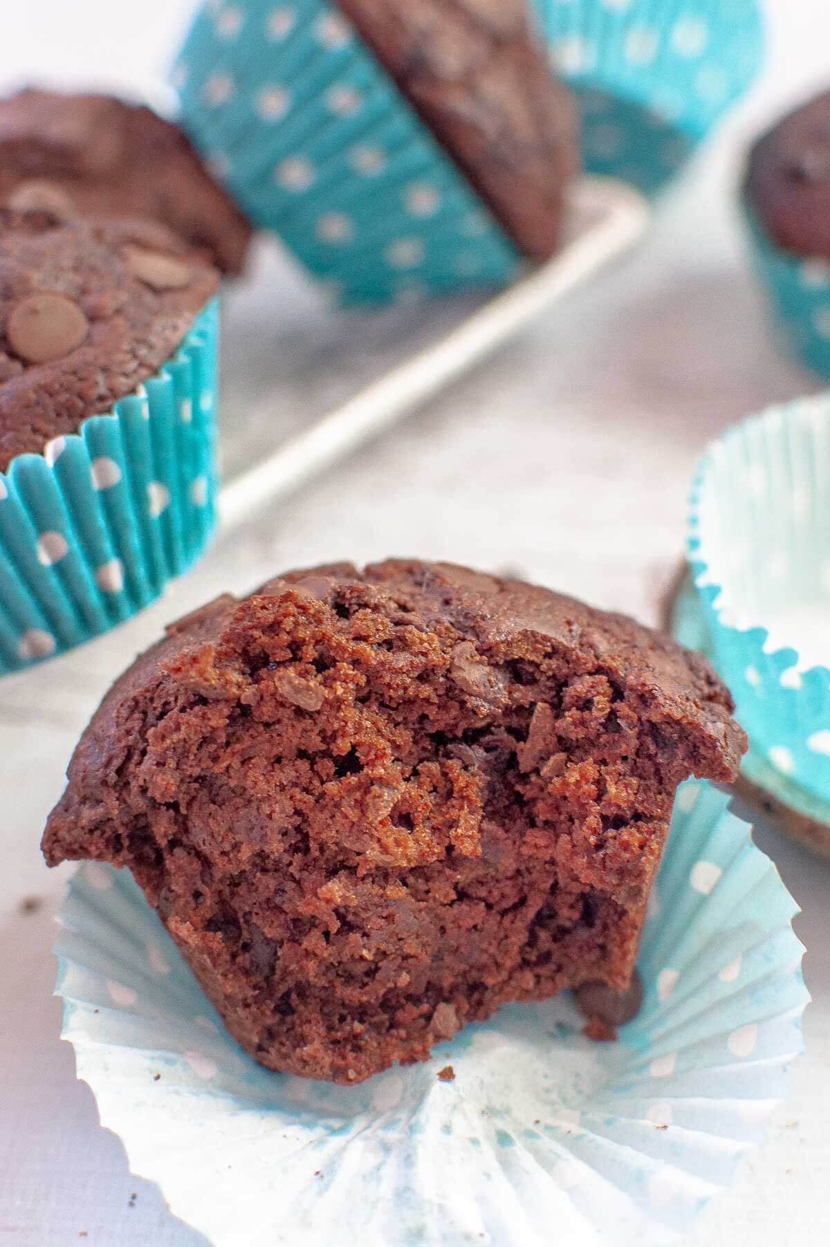 a single chocolate muffin in a paper case half eaten