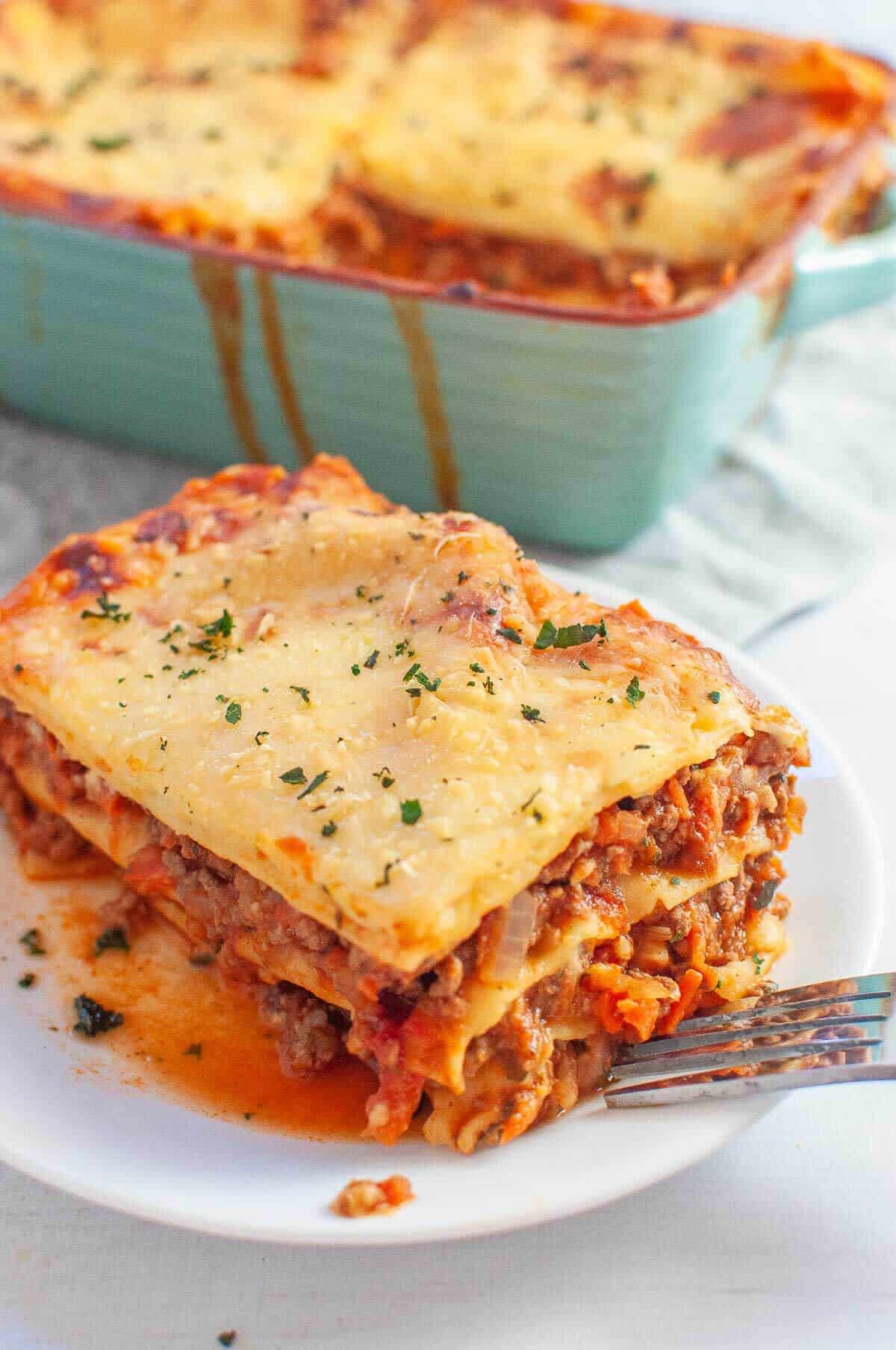 a serve of lasagna without ricotta on a white plate with a fork