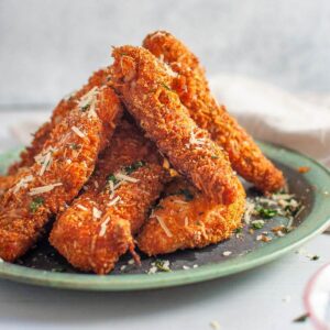 paprika chicken fingers staked on a green plate