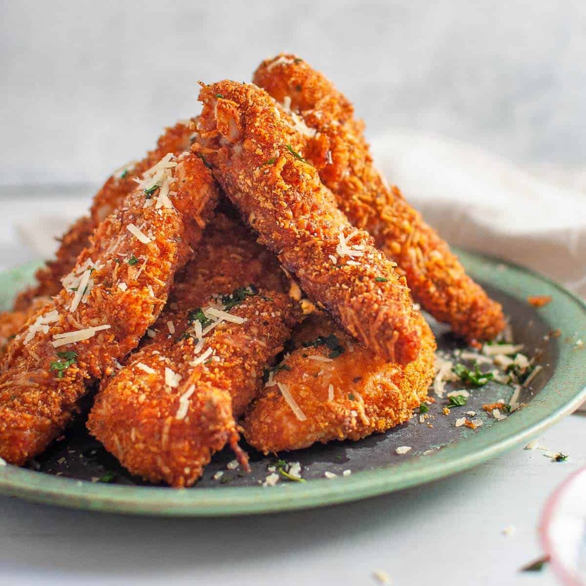 a stack of six chicken tenders on a green plate