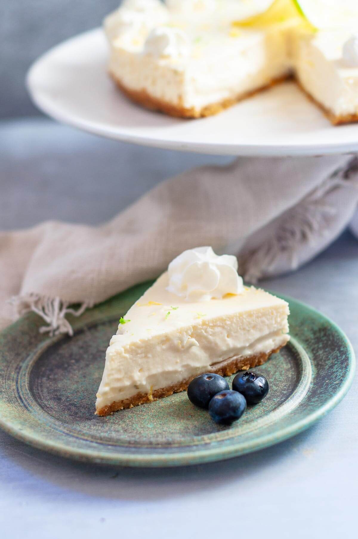 a slice of cheesecake on a green plate with blueberries