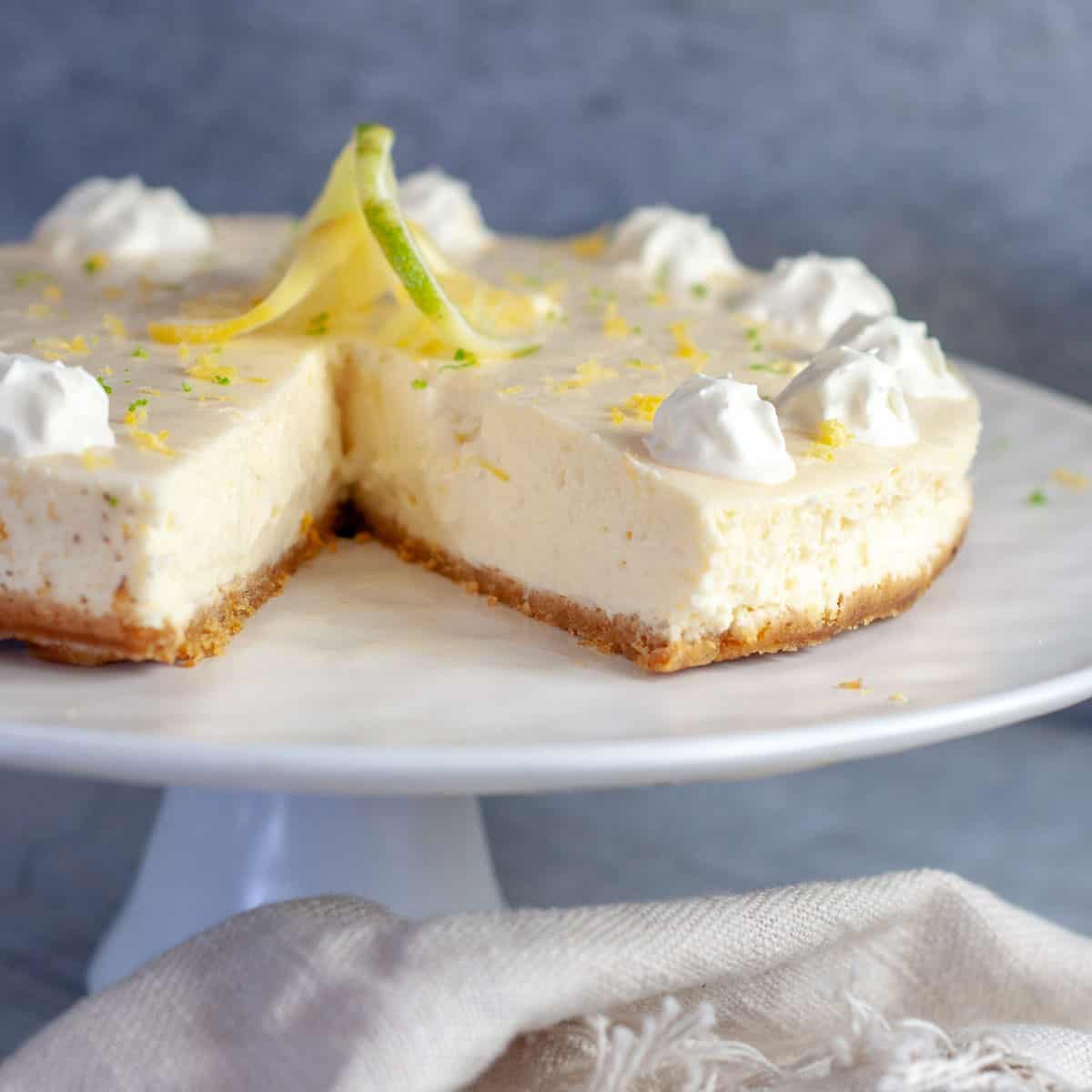 Lemon and Lime Cheesecake on a serving platter with slice out