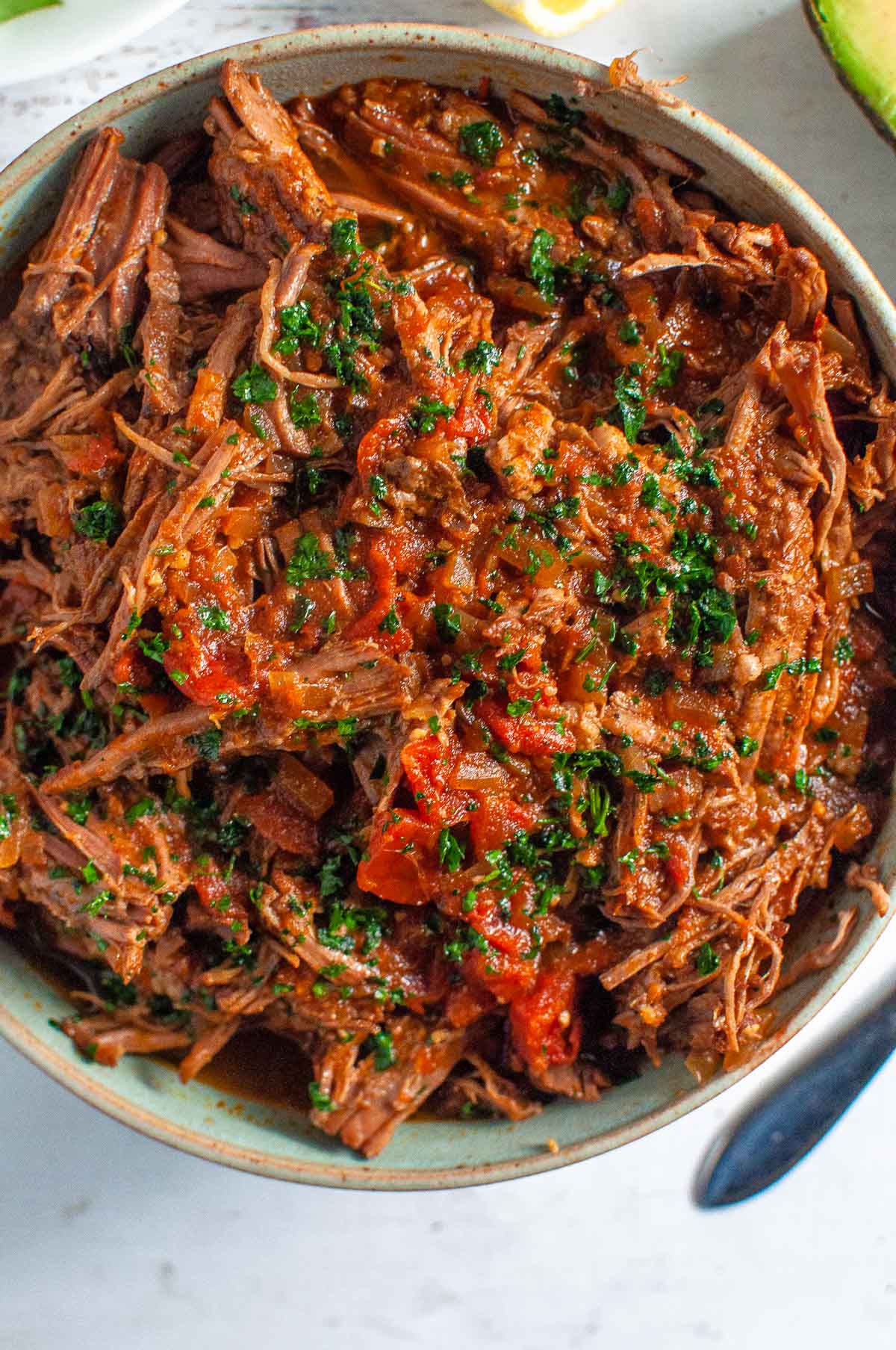 a big bowl of smoky beef brisket with parsley on top