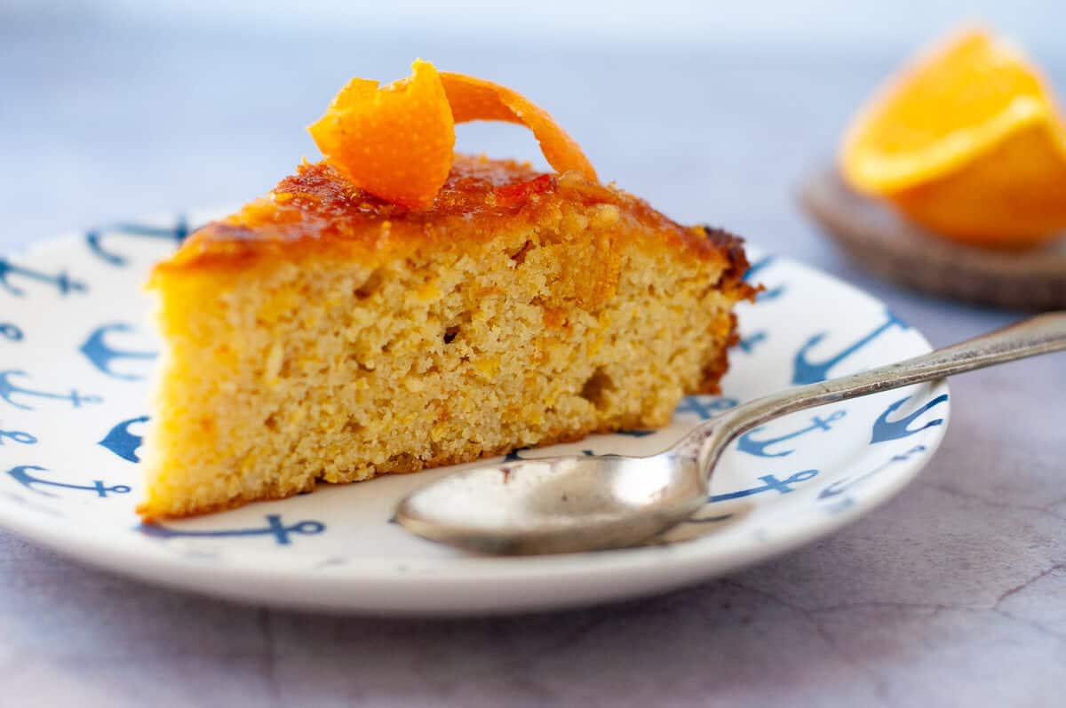 a slice of orange cake on a plate with spoon