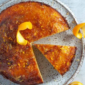 sliced orange cake on a plate with slices of decorative orange rind