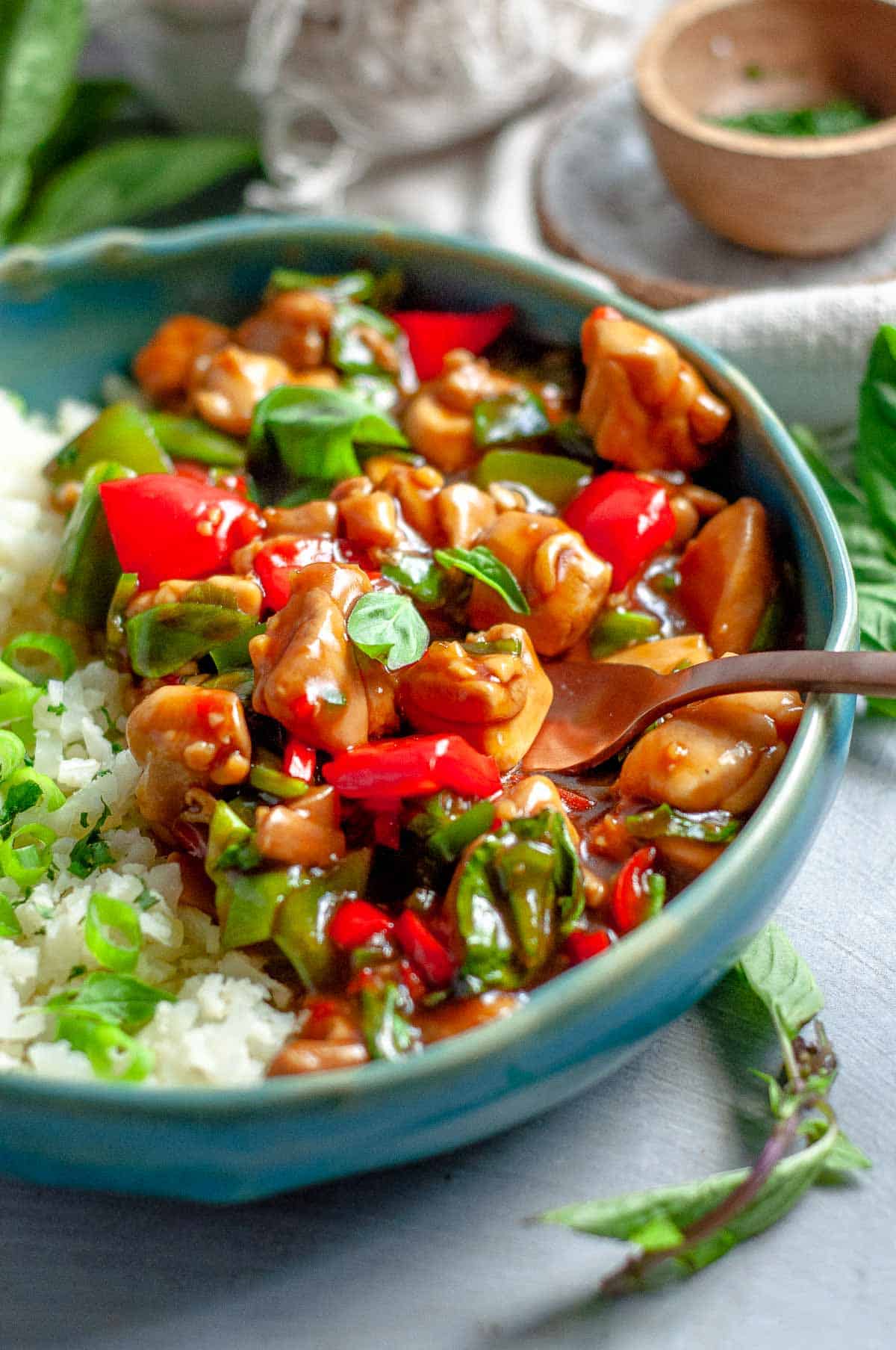 Thai basil chicken in a blue bowl with a fork in