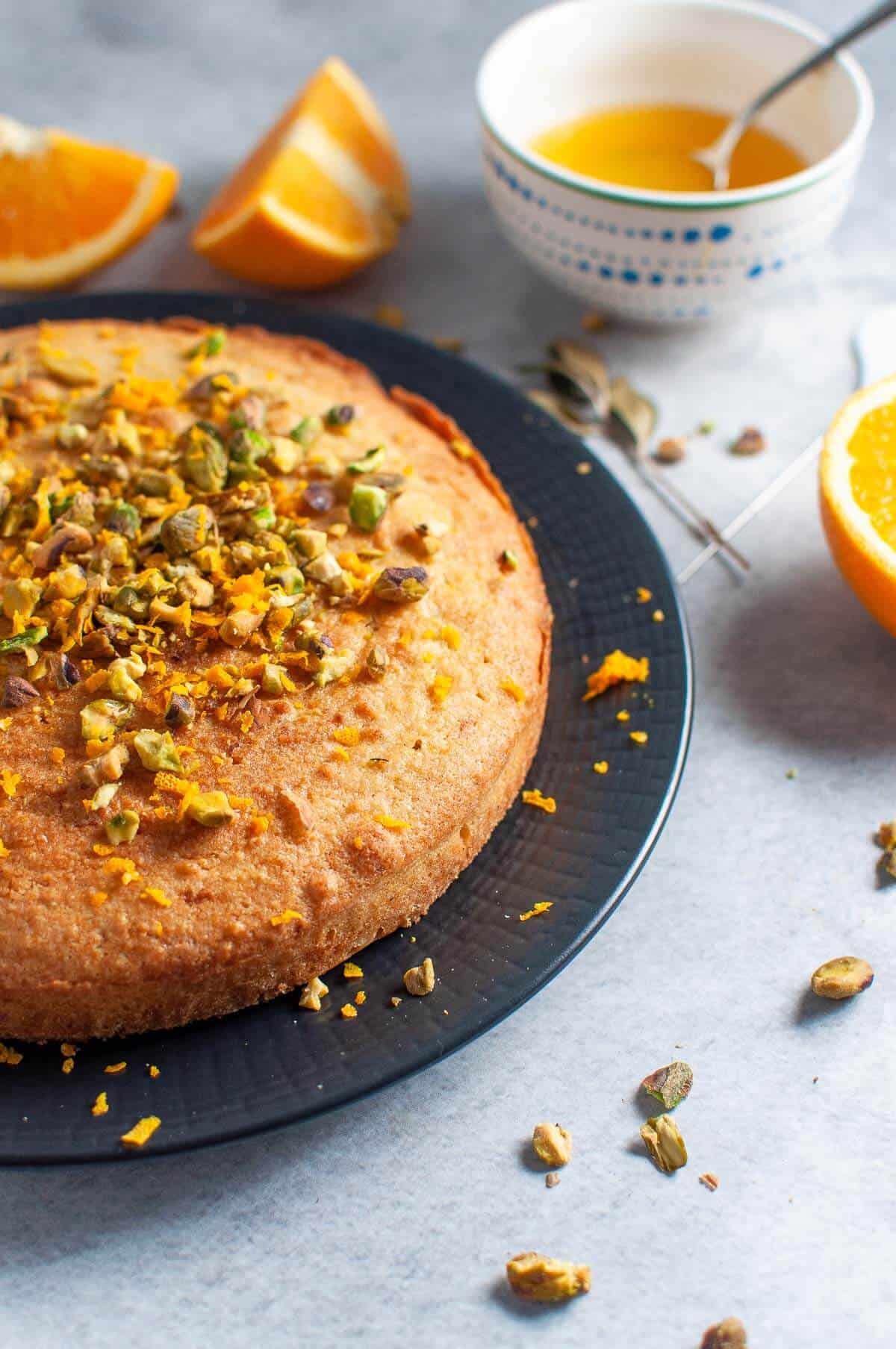 unsliced orange polenta cake on a black plate