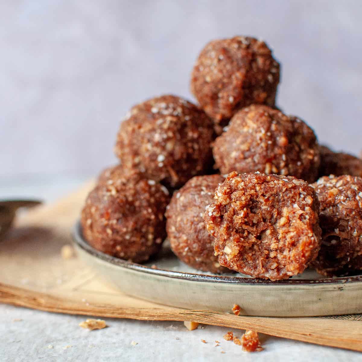 bliss balls stacked on a plate and one with a bite out
