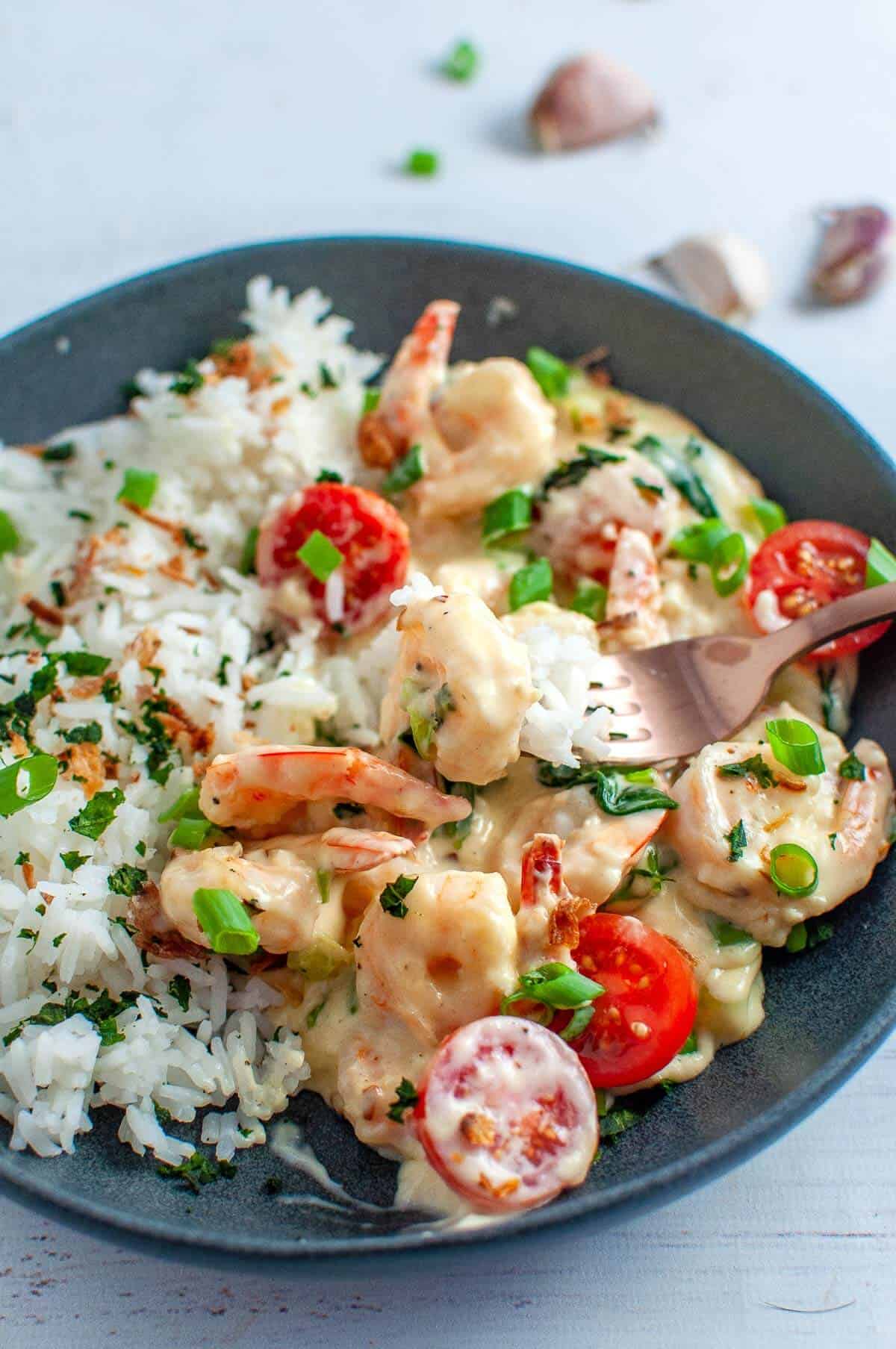 fork digging into a bowl of creamy garlic prawns and rice