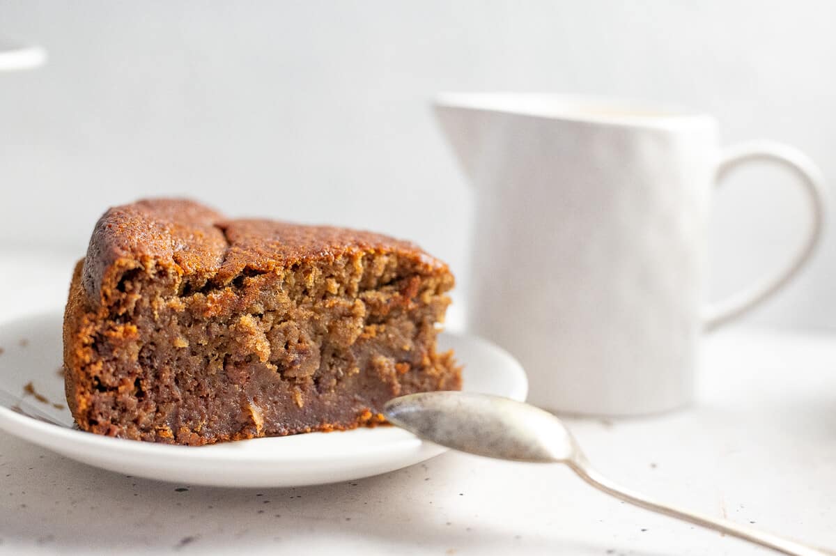 a slice of pudding with a jug of custard