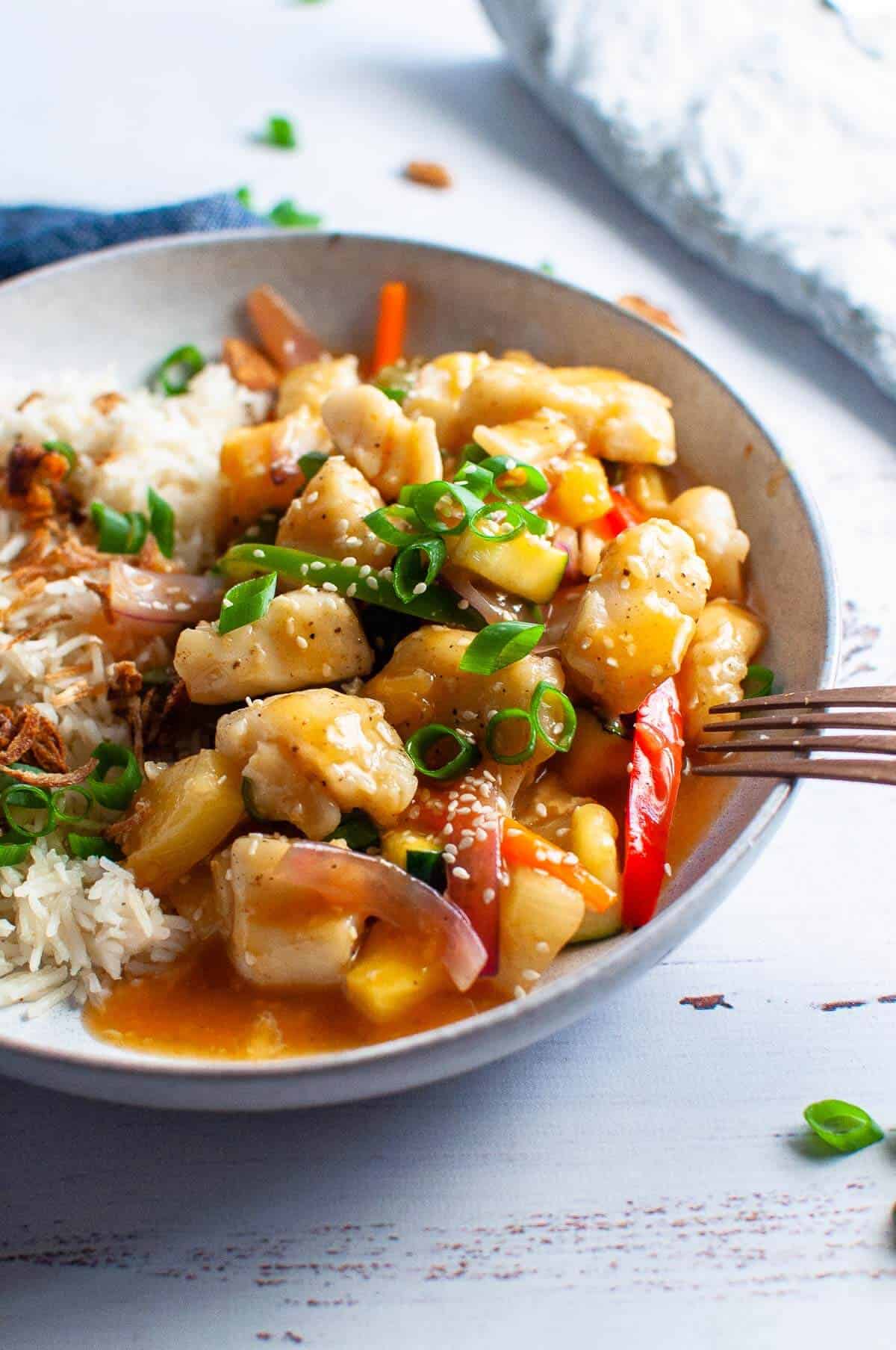 sweet and sour fish with rice in a bowl with fork ready to eat