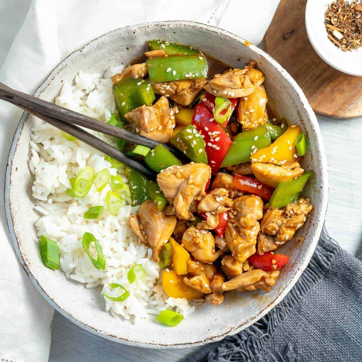 a bowl of teriyaki chicken and rice with chopsticks