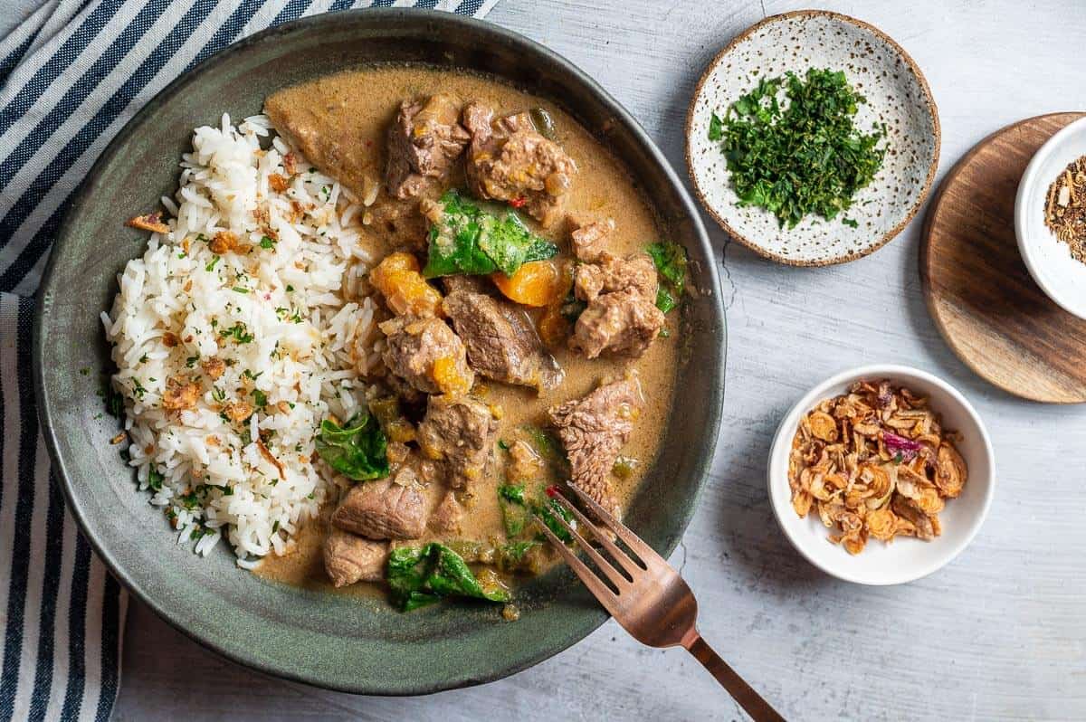 a bowl of thai beef curry with dried shallots and corriander