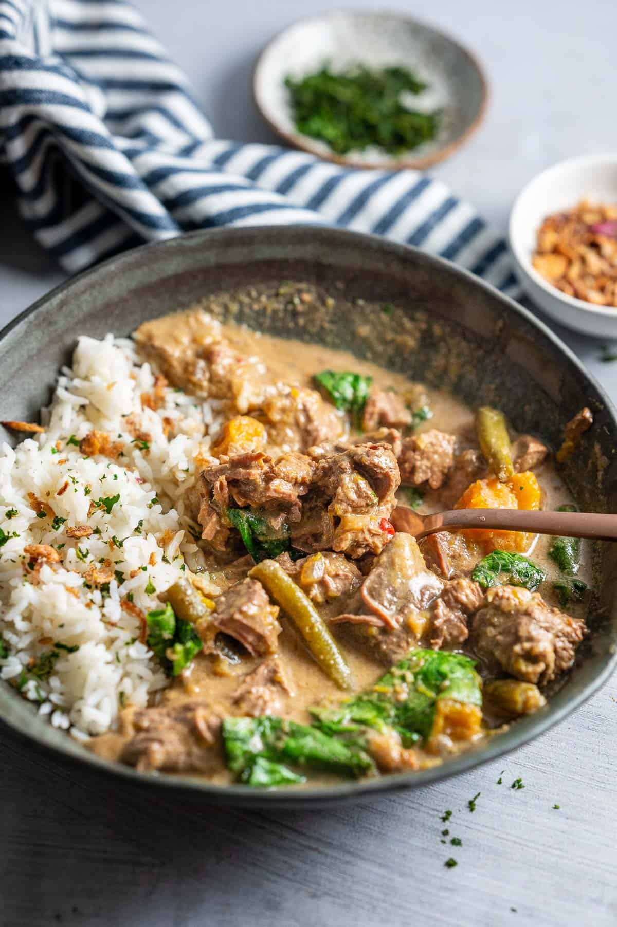 a bowl of thai green beef curry with rice with a fork in