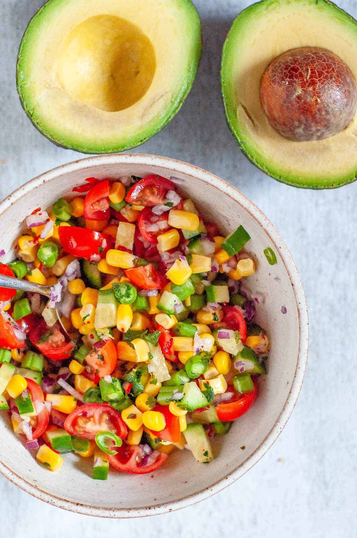 avocado halved and a bowl of chopped mexican salsa