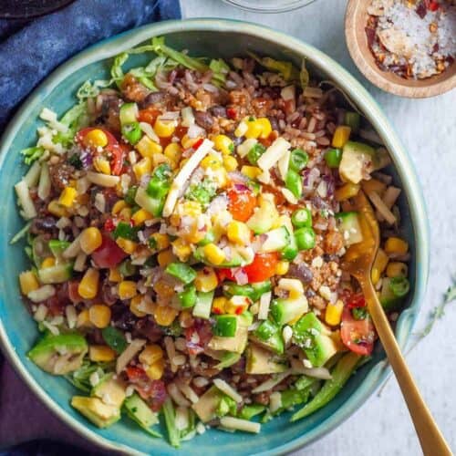 healthy ground beef burrito bowl with toppings in a blue bowl