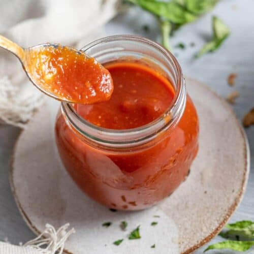 a spoon dipped into a jar of sweet and sour sauce