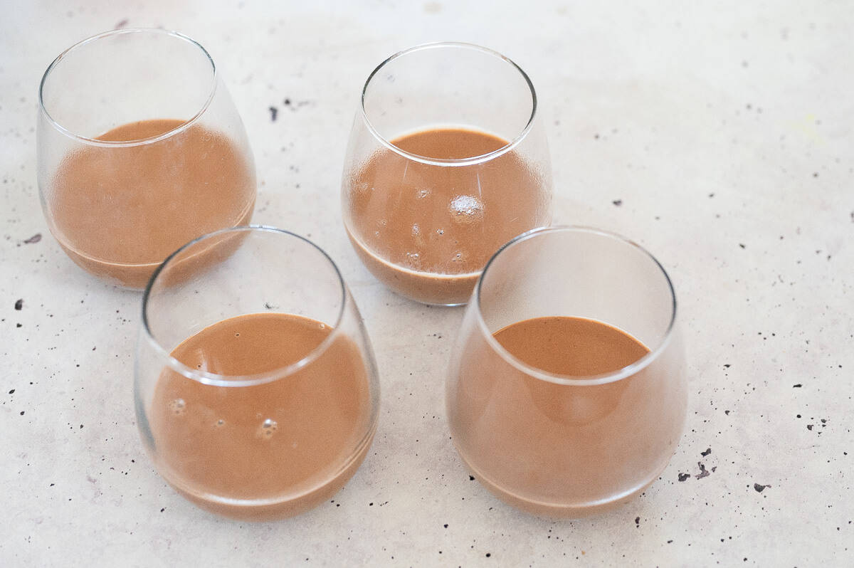 Four glasses filled with chocolate panna cotta liquid