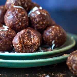a stack of cocao bliss balls on 2 green plates