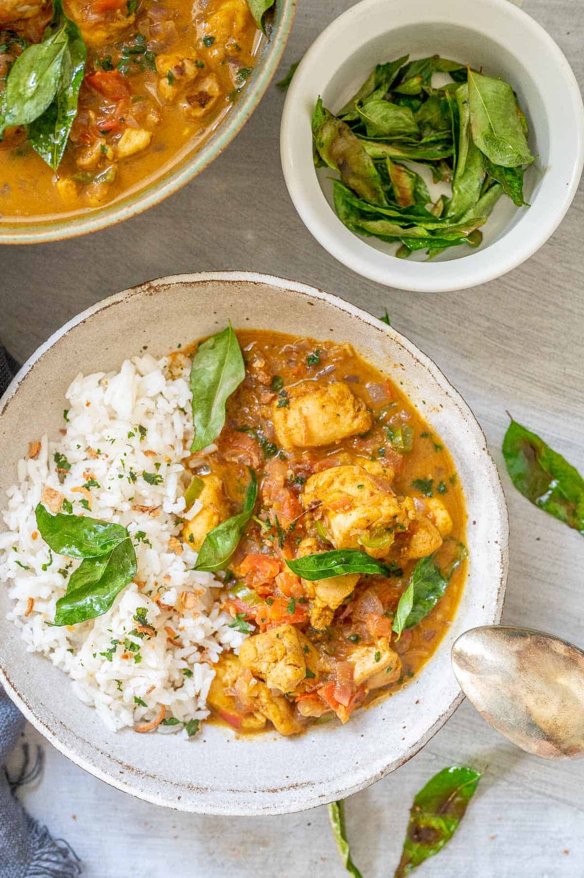 a bowl of chicken kerala curry with curry leaves