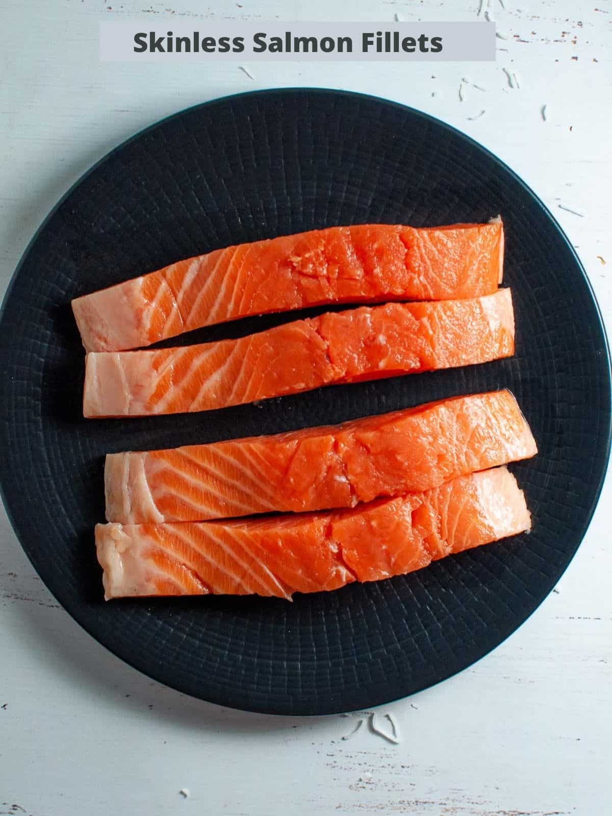 four skinless salmon fillets on a black plate