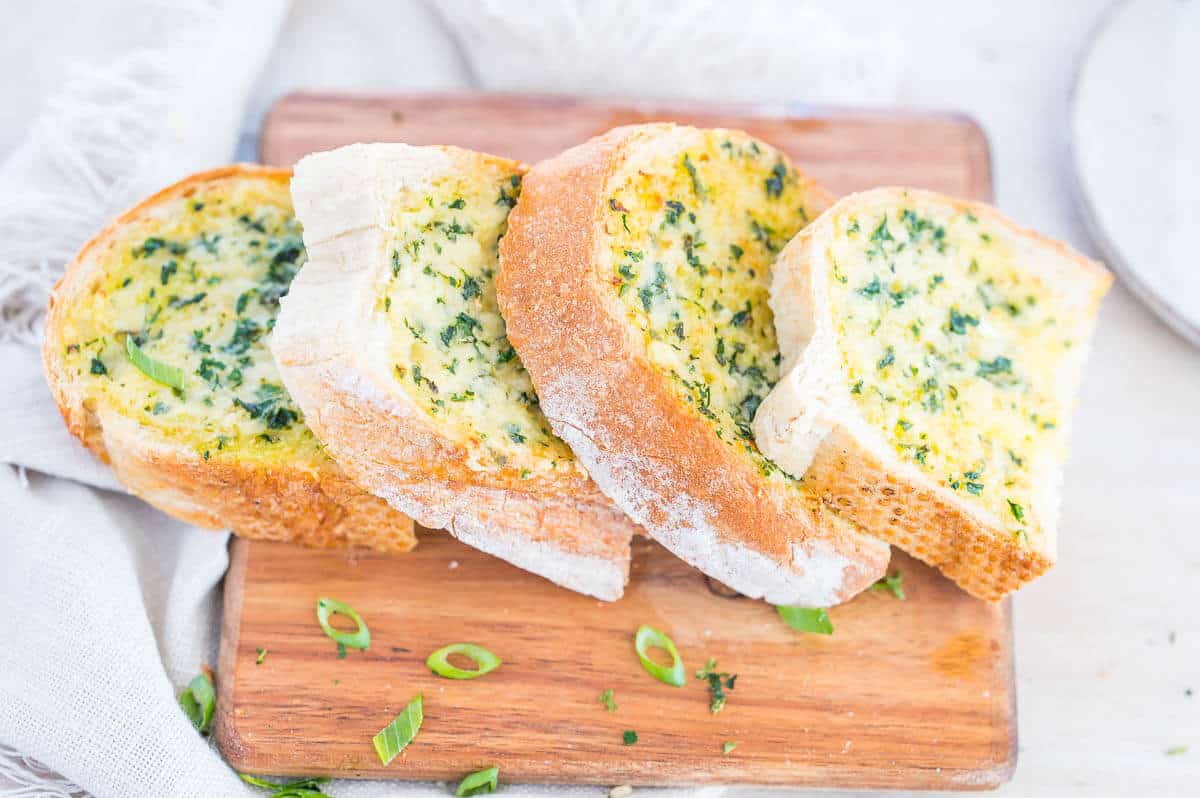 four slices of garlic bread on wooden chopping board