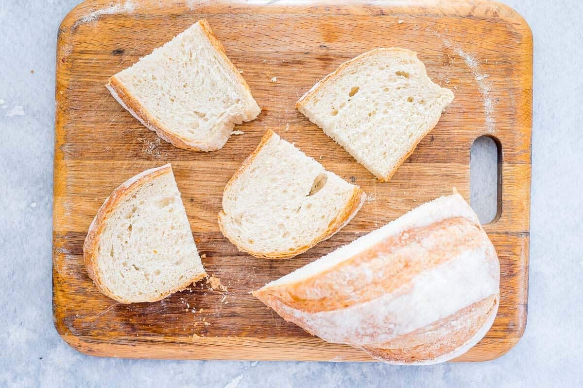 crusty loaf of bread cut up on a board